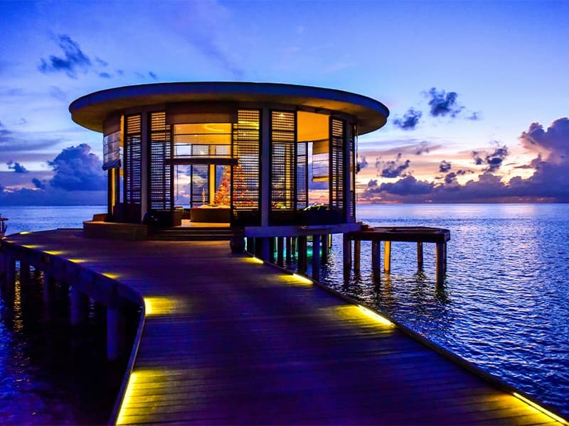 Image of a luxury "hut" down a walkway over the ocean