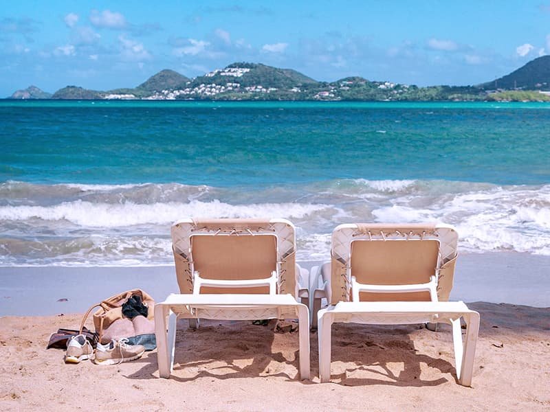 Two lounging chairs at the edge of the beach overlooking the ocean