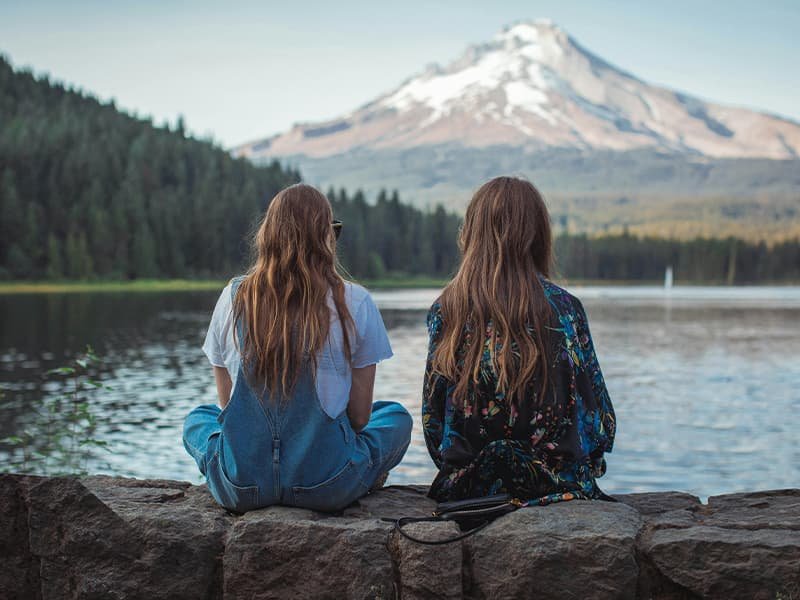 Two girls sitting in front of a lake in Oregon