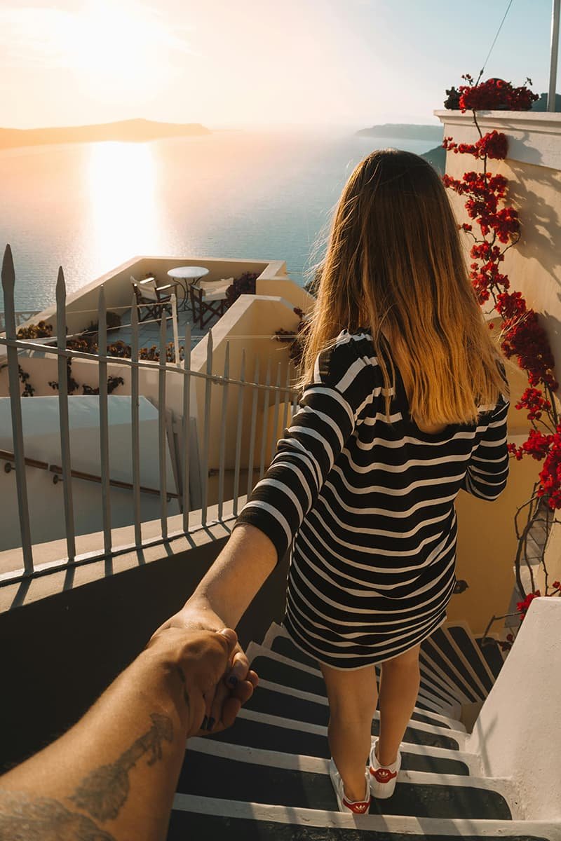 Woman leading man down stairs overlooking ocean